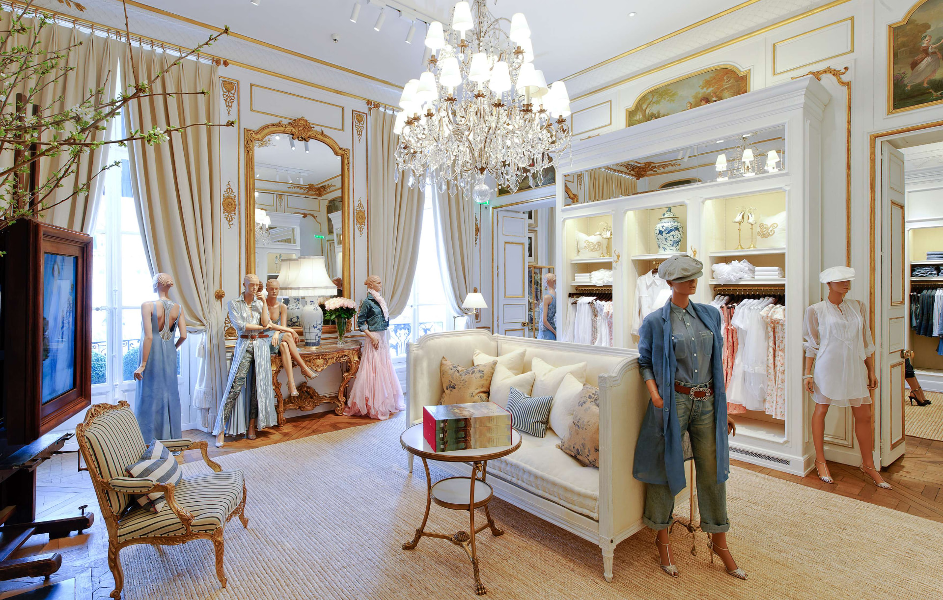 Ralph Lauren boutique salon with crystal chandelier, gilded mirror, cream sofa and styled mannequins