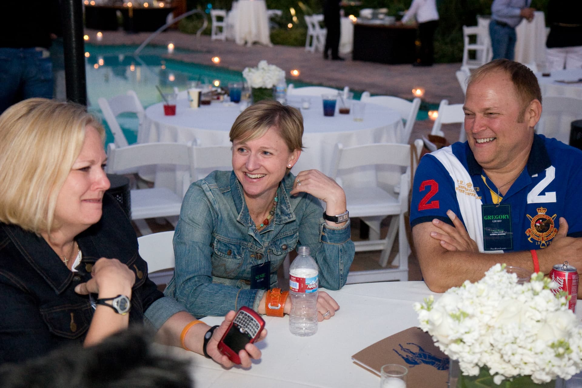 Guests laughing together at a poolside dinner table during the Rancho Bernardo conference