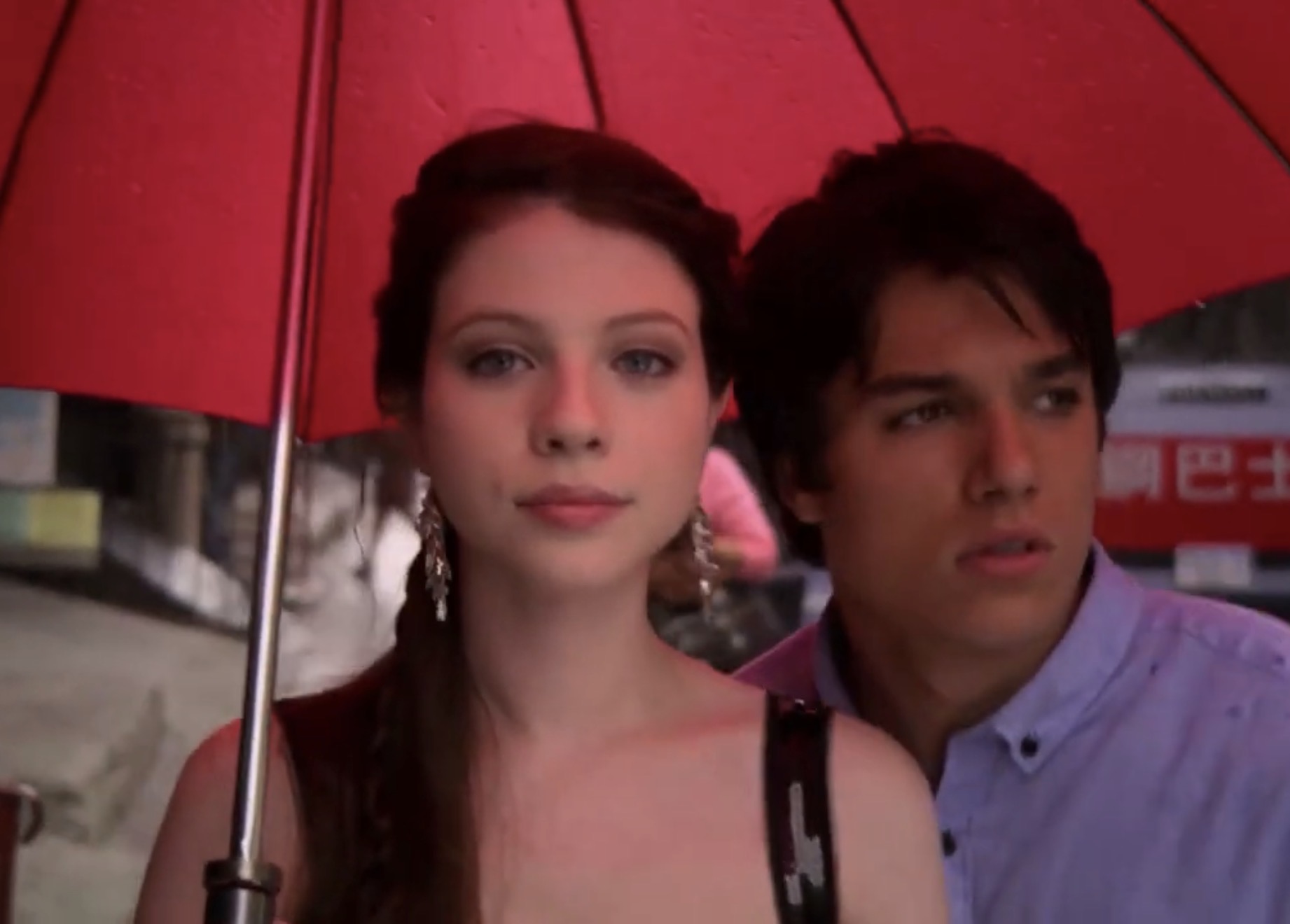 Chris Riggi with a fellow cast member beneath a red umbrella in Gossip Girl