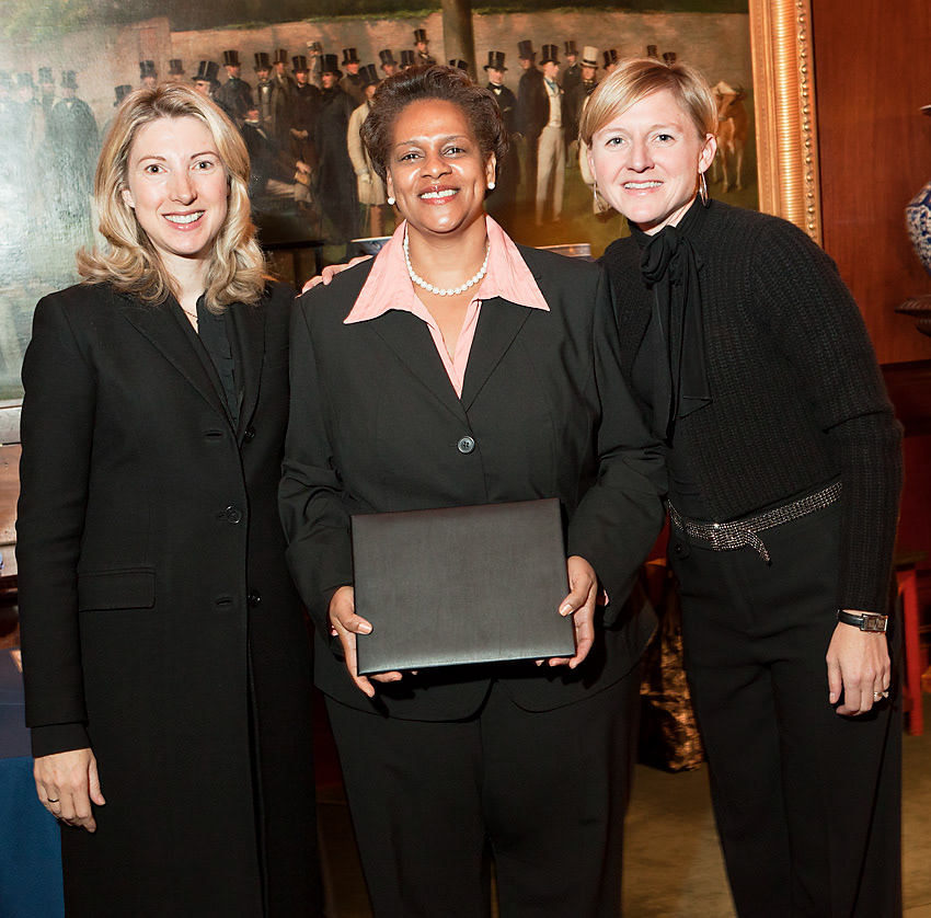 Honoree holding a presentation folder between two hosts