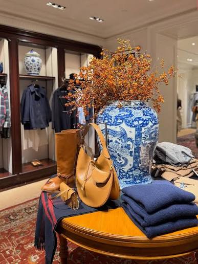 Blue-and-white porcelain vase with orange branches, leather boots and handbag on a round table