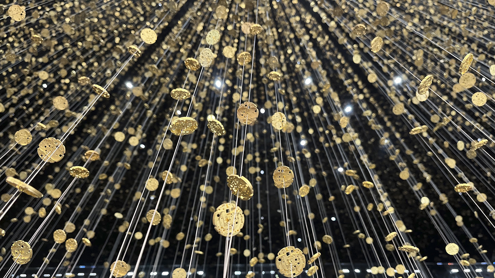 Close-up of suspended gold watch components in the Light Is Time installation