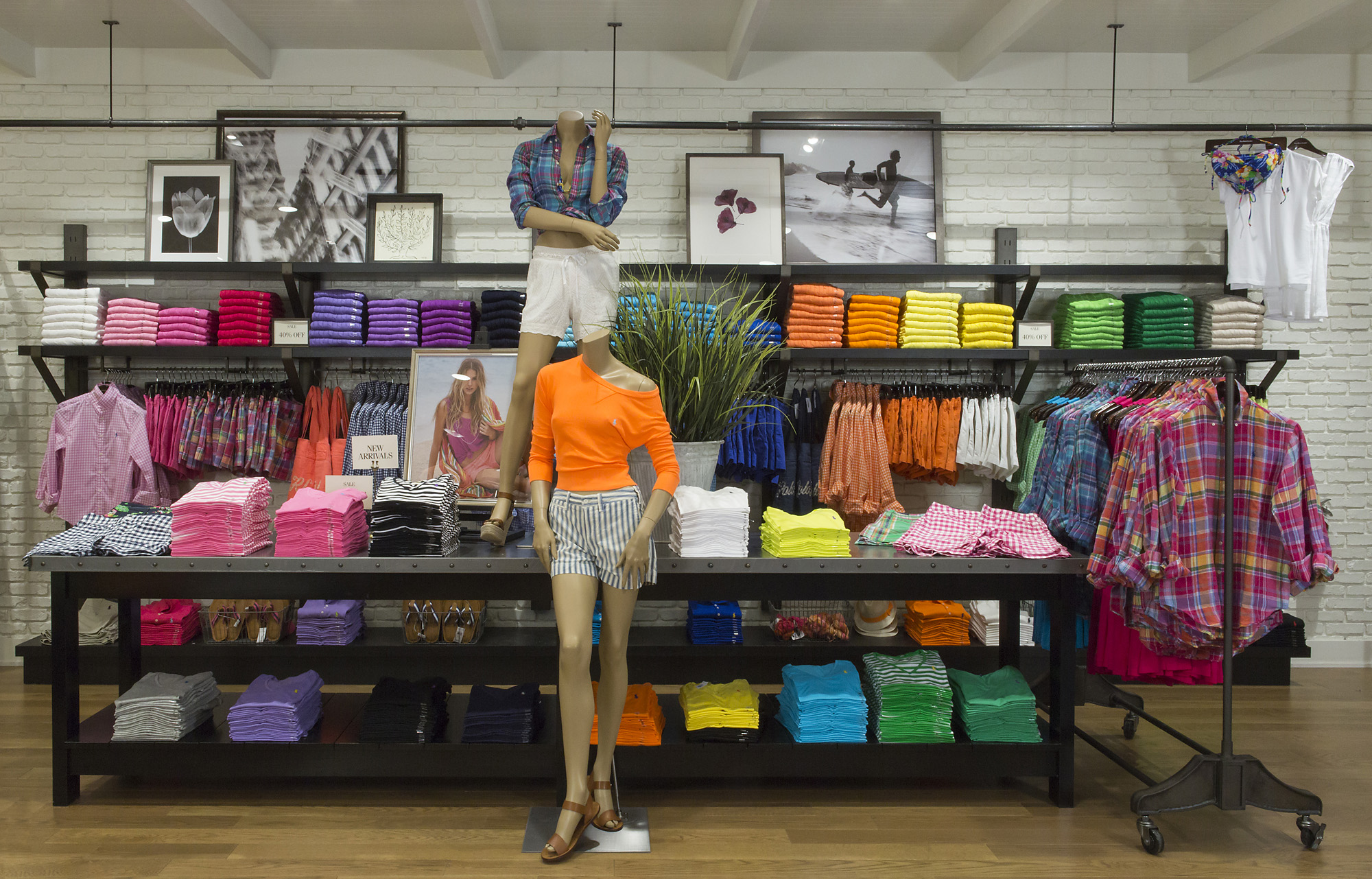 Wall of color-blocked folded sportswear behind styled mannequins