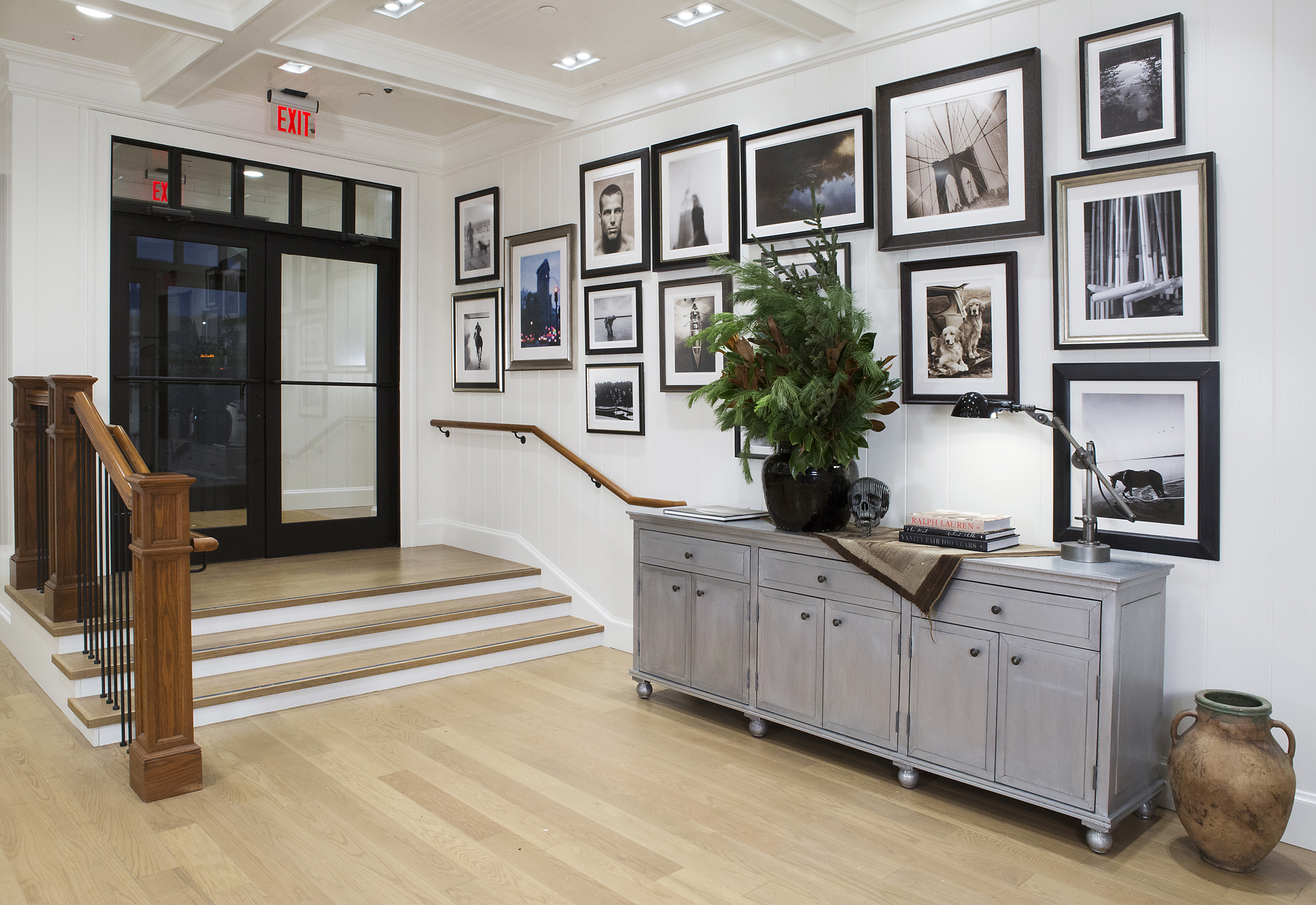 Gallery wall of black-and-white photographs above a grey sideboard with greenery