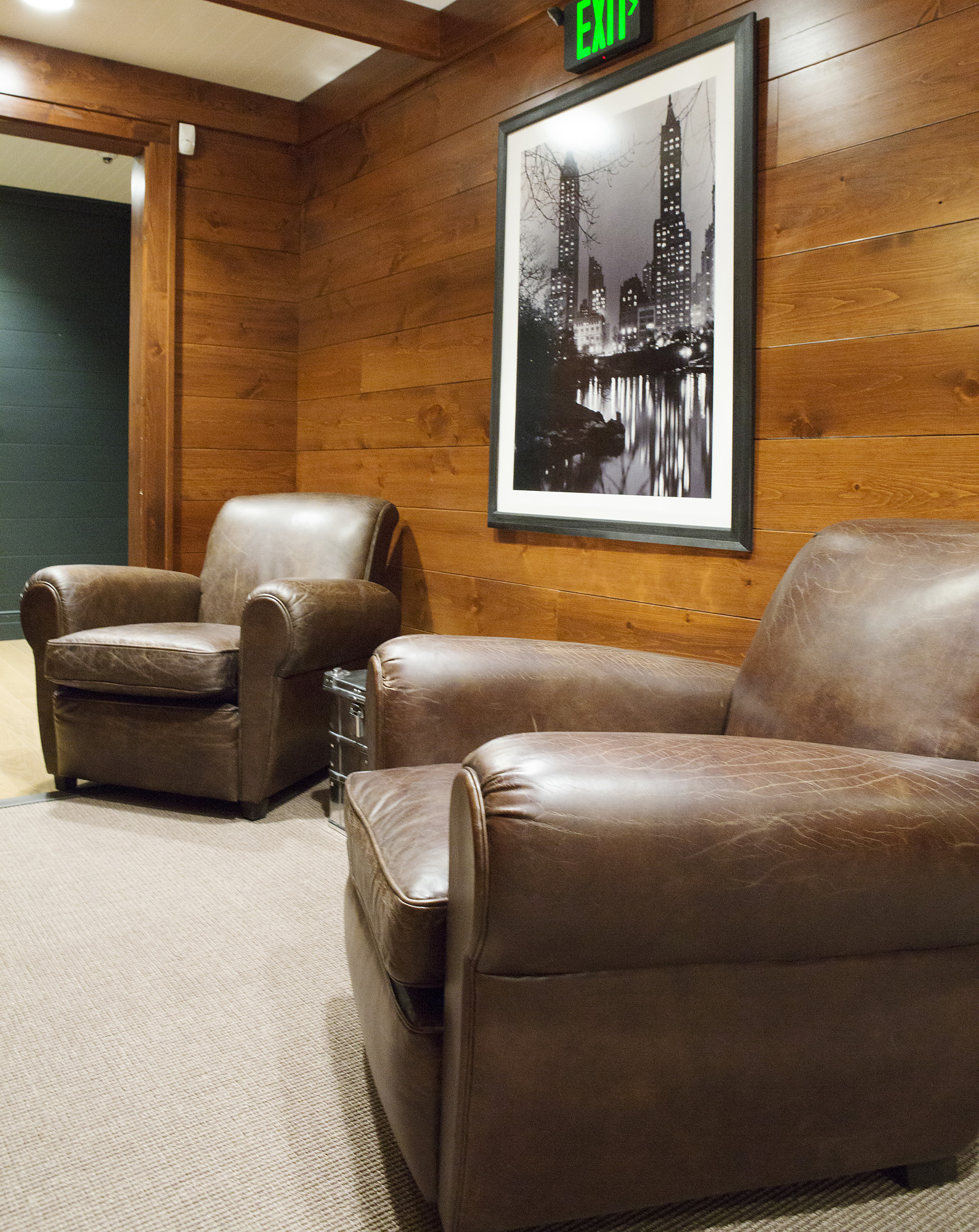 Ralph Lauren lounge with distressed leather club chairs, wood-paneled walls and a framed black-and-white Central Park photograph
