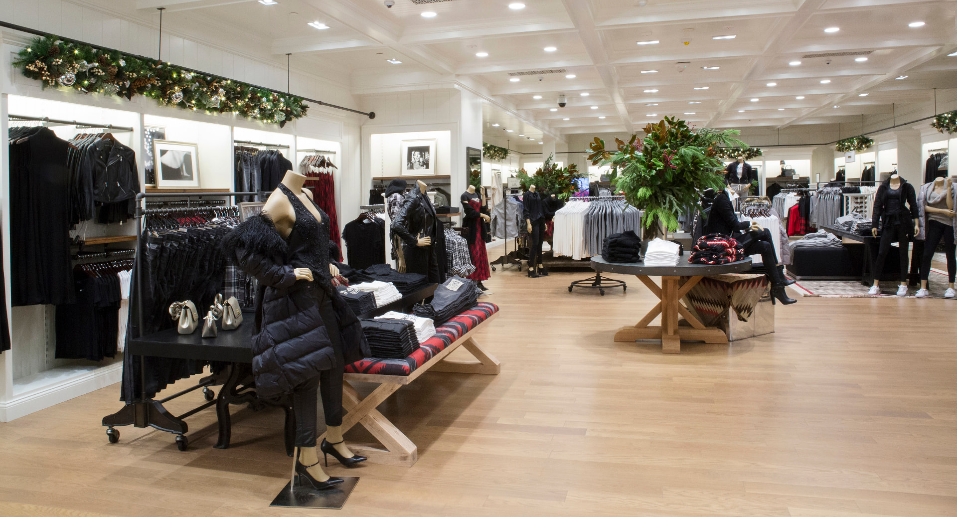 Women's selling floor with black clothing, holiday greenery and a central floral arrangement
