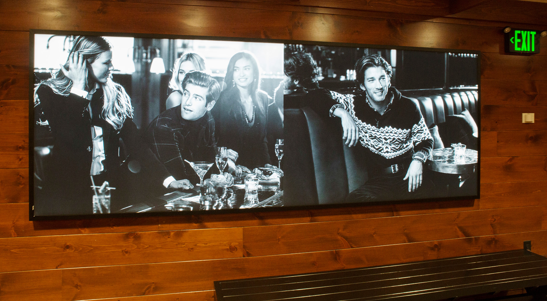 Panoramic black-and-white lifestyle imagery on a wood-paneled wall