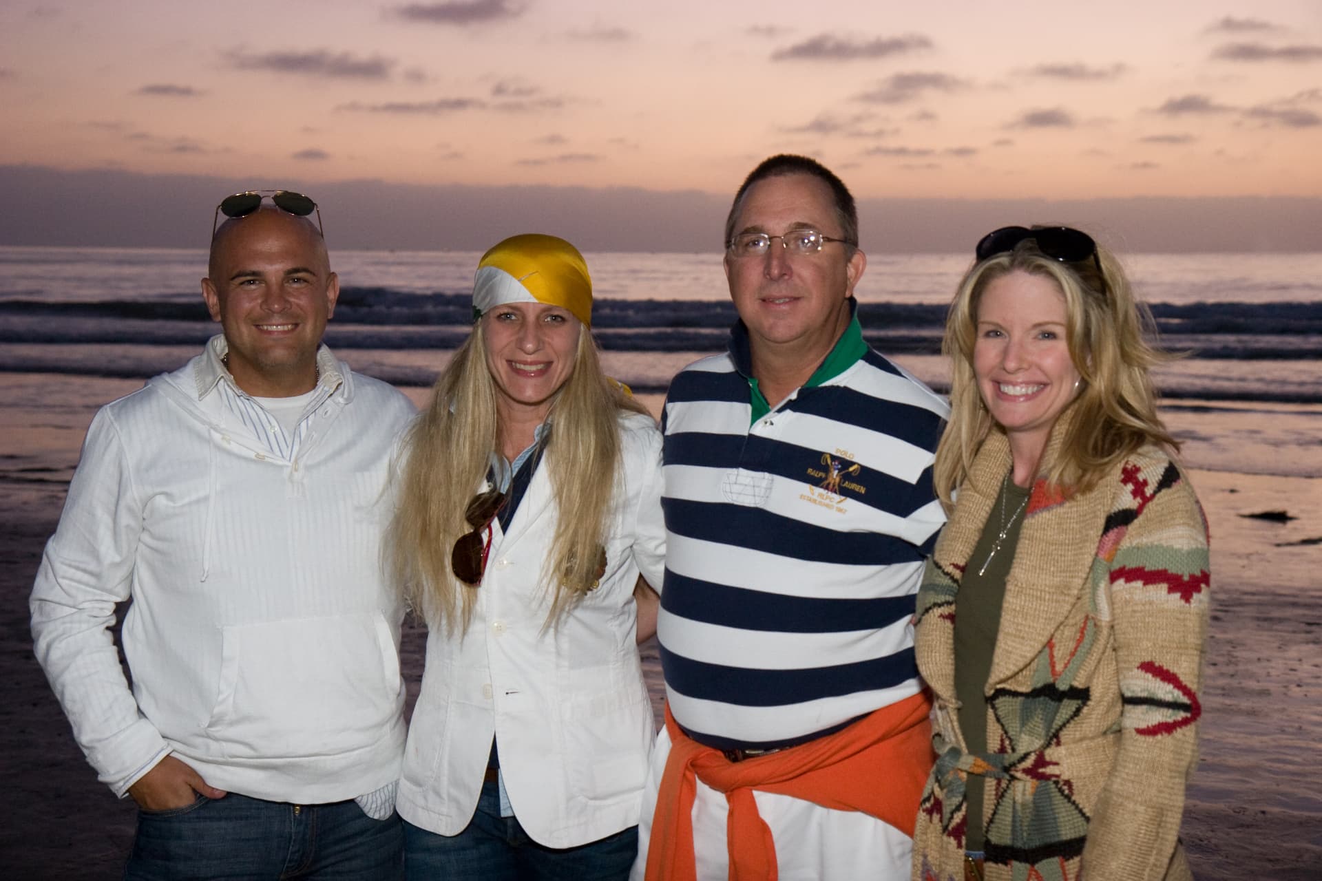 Two couples posing together on the beach at sunset at the La Jolla event, with the ocean behind them