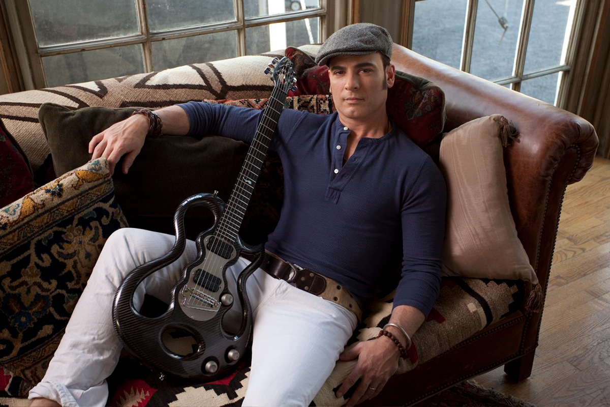 Rod DeGeorge in a blue henley and white trousers on a leather sofa