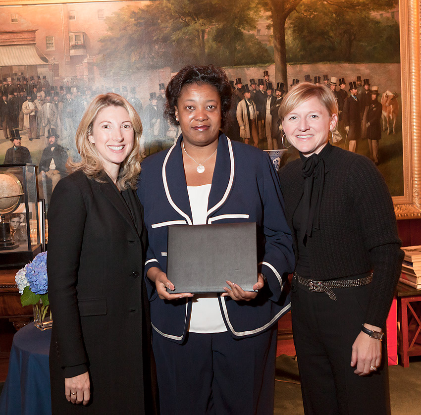 Honoree holding a presentation folder between two hosts